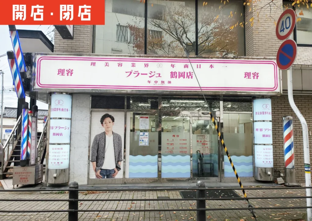 鶴岡駅前の理容プラージュ外観。店頭の看板と告知が確認できる様子を写した写真。