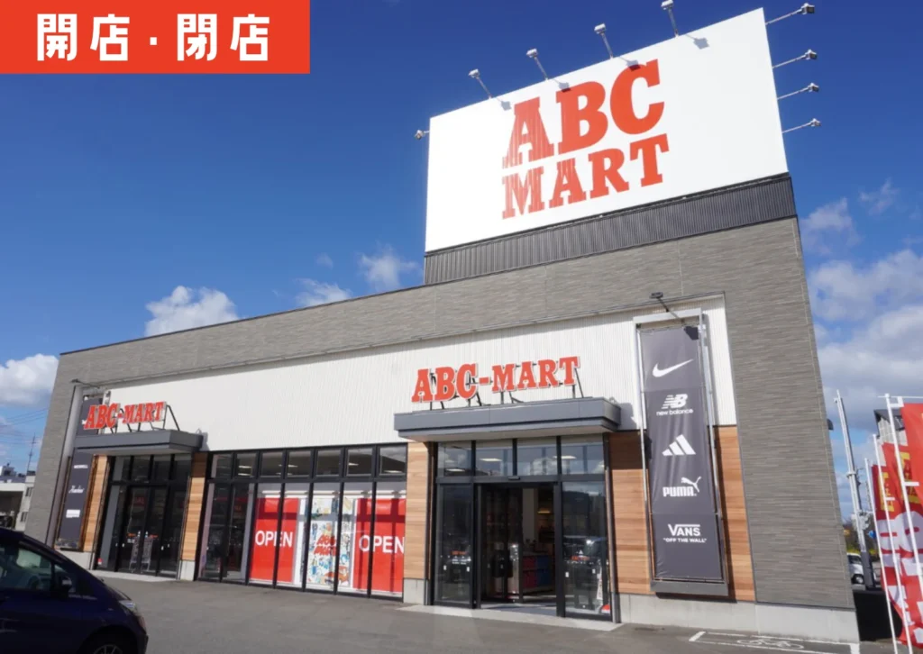 青空の下、白基調の外観にリニューアルされた「ABC-MART 鶴岡店」の建物を正面から撮影した様子。入口ガラス越しに「OPEN」の赤い表示が見える。