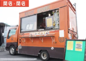 遊佐町を中心に営業する多国籍料理のキッチンカー「Fuuten kitchen八兵衛」のオレンジ色の移動販売車。窓口で調理する店主の姿が見える。