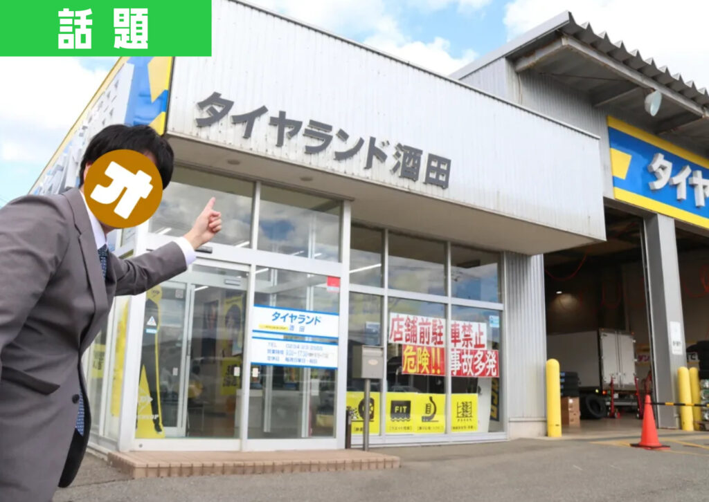 タイヤランド酒田店の前で編集部員の「オタク」が指を指すポーズをしている様子