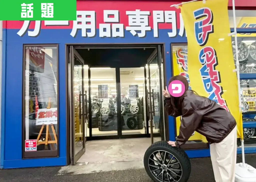 鶴岡市西新斎町のアップガレージ山形鶴岡店の前でタイヤを持った編集部員がポーズをとっている