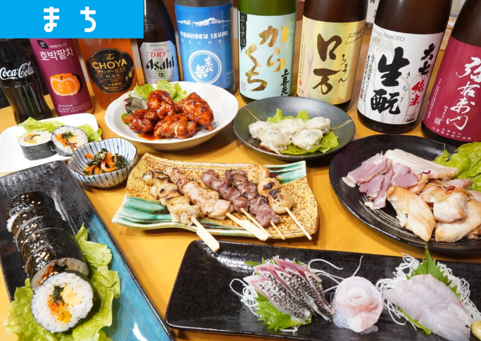 豪華にテーブルに並べられた、燻製肉や韓国グルメをはじめとする宴会料理。奥には地酒や福島県の日本酒も見える。